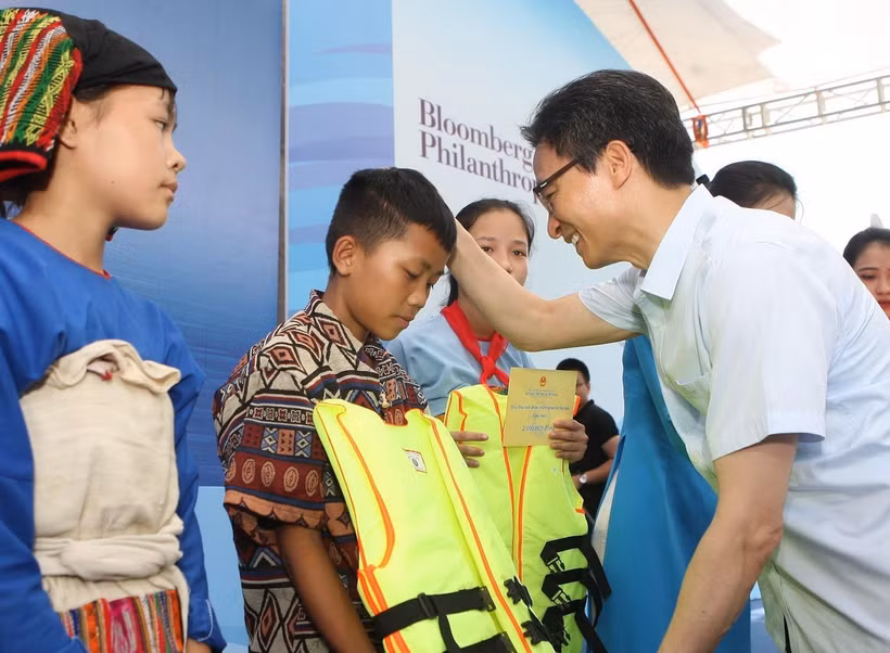 Phó Thủ tướng Chính phủ Vũ Đức Đam tặng áo phao cho các em nhỏ tại buổi lễ. (Ảnh: Thanh Tùng/TTXVN)