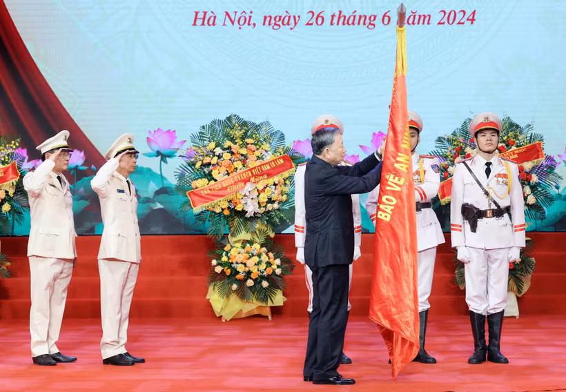 Chủ tịch nước Tô Lâm gắn Huân chương Chiến công hạng Nhì lên cờ truyền thống của Lực lượng kỹ thuật nghiệp vụ Công an Nhân dân. (Ảnh: Nhan Sáng/TTXVN)