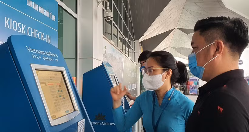 Nhân viên Vietnam Airlines hướng dẫn giúp hành khách làm thủ tục trực tuyến tại Kios check-in online ở một sân bay. (Ảnh: CTV/Vietnam+)