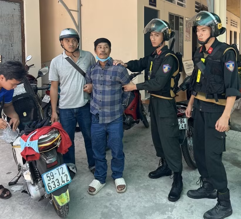 Đối tượng Trương Văn Út (áo sọc đen) bị tạm giữ vì liên quan đến vụ án giết người. (Ảnh: TTXVN phát)