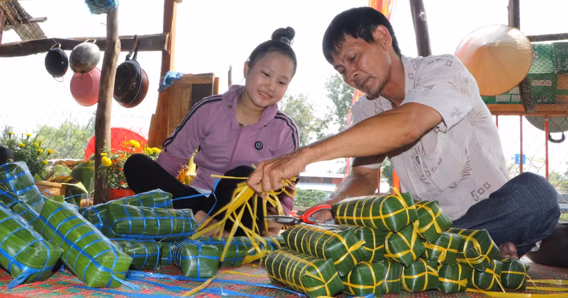 Không khí sum vầy của ngày Tết trong dịp gói bánh tét. (Ảnh: Nguyễn Hằng/TTXVN)