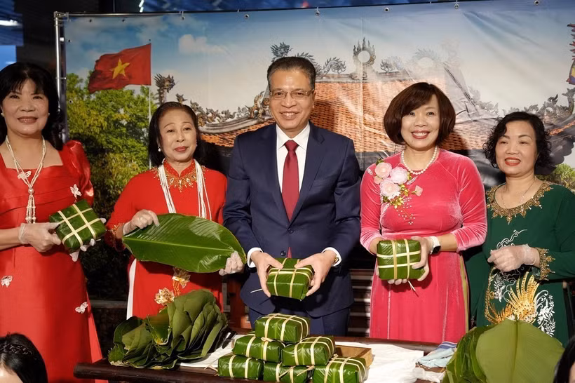 Đại sứ Việt Nam tại Liên bang Nga Đặng Minh Khôi (giữa) và Phu nhân (thứ 2, phải qua) cùng bà con cộng đồng gói bánh chưng. (Ảnh: TTXVN)