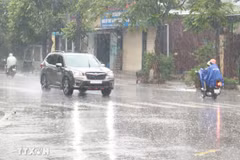 Người dân đi lại trong mưa lớn. (Ảnh: Nguyên Lý/TTXVN)