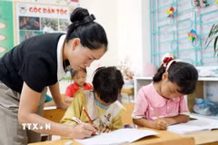 Giáo viên Trường Phổ thông Dân tộc Bán trú Tiểu học và Trung học cơ sở Thu Lũm hướng dẫn học sinh lớp 1 tập viết chữ. (Ảnh: Quý Trung/TTXVN)