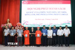 Đại diện xã Gia Bình trao tặng cuốn lịch sử thôn cho các thôn bị di dời phục vụ Dự án Cảng hàng không quốc tế Gia Bình. (Ảnh: Thanh Thương/TTXVN)