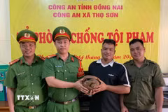 Anh Điểu Khanh (thứ 2, từ phải qua), giao nộp cá thể Tê Tê Java, có trọng lượng khoảng 3kg cho cơ quan công an xã Thọ Sơn. (Ảnh: Đậu Tất Thành/TTXVN)