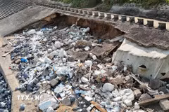 Đoạn kè ven biển dài khoảng 60m bị sóng biển khoét sâu vào trong, lộ ra xi măng, cốt thép, đất... (Ảnh: Thanh Thủy/TTXVN)