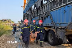 Lực lượng chức năng đưa thi thể nạn nhân ra ngoài. (Ảnh: TTXVN phát)