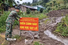 Lực lượng chức năng xã Quảng Sơn căng dây, cắm biển cảnh báo tại khu vực sạt lở ở thôn Đắk Snao. (Ảnh: Nguyễn Huy Thành/TTXVN)