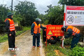 Cán bộ, chiến sỹ Bộ đội Biên phòng Quảng Trị phối hợp lắp đặt biển cảnh báo tại khu vực nước sâu, nguy hiểm, chủ động phòng ngừa tai nạn trong mùa mưa lũ. (Ảnh: TTTXVN phát)