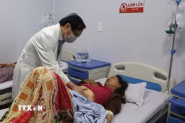 Bác sỹ kiểm tra sức khỏe cho bệnh nhân nhập viện nghi ngộ độc thực phẩm do ăn bánh mỳ. (Ảnh: Đinh Hương/TTXVN)