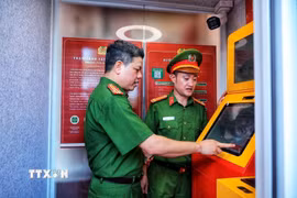 Thượng tá Nguyễn Thành Lâm (bên trái) cùng cán bộ Công an trải nghiệm hoạt động của Kiosk “Trạm Cảnh sát thông minh” trước khi đưa vào phục vụ người dân. (Ảnh: Phạm Tuấn Anh/TTXVN)