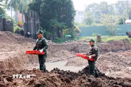 Chiến sỹ đội K74 đưa di cốt liệt sỹ từ hố khai quật tới phòng lấy mẫu, lưu mẫu xác định danh tính liệt sỹ. (Ảnh: Xuân Khu/TTXVN)