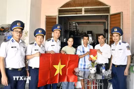 Các lực lượng chức năng trao cờ và hướng dẫn cho ngư dân khai thác hải sản đúng pháp luật. (Ảnh: Trần Tĩnh/TTXVN)