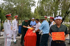 Nghi thức phủ cờ Tổ quốc lên hài cốt liệt sỹ Bùi Tiến Dũng. (Ảnh: Đoàn Mạnh Dương/TTXVN)
