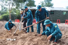 Lực lượng chức năng tìm kiếm hài cốt liệt sỹ khu vực Gò Tràm, thôn An Sơn. (Ảnh: Phạm Cường/TTXVN)