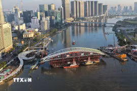 Toàn cảnh sà lan chở nhịp chính được đưa vào vị trí hợp long dự án cầu đi bộ qua sông Sài Gòn. (Ảnh: Minh Linh/TTXVN)