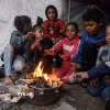 Trẻ em Palestine sưởi ấm tại khu lều trại tạm ở thành phố Gaza. (Ảnh: THX/TTXVN)