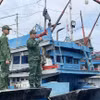 Bộ đội biên phòng dùng loa phóng thanh kêu gọi các tàu cá sắp xếp neo đậu an toàn tại cảng cá Sa Huỳnh. (Ảnh: Phạm Cường/TTXVN)