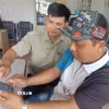 Nhân viên Văn phòng kiểm tra, kiểm soát nghề cá cảng Cát Lở, phường Phước Thắng, Thành phố Hồ Chí Minh hướng dẫn chủ tàu cá làm thủ tục xuất bến điện tử 2. (Ảnh: Hoàng Nhị - TTXVN)