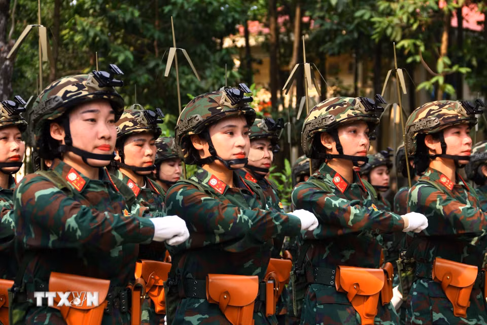 Các nữ chiến sỹ vẫn nỗ lực tập luyện dù phải đội mũ và đeo máy vô tuyến điện có trọng lượng khoảng hơn 4kg. (Ảnh: Lê Xuân/TTXVN)