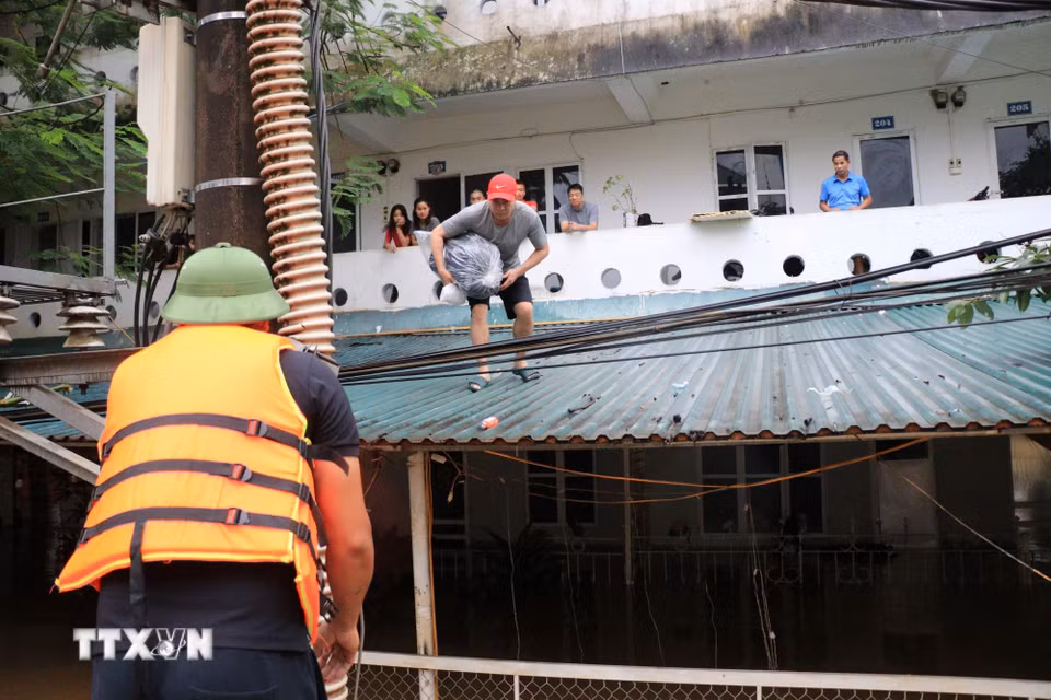 Lực lượng chức năng hỗ trợ người dân di chuyển đến nơi an toàn. (Ảnh: Tuấn Anh/TTXVN)