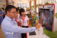 Cán bộ hướng dẫn học sinh trải nghiệm Kiosk dịch vụ công tại không gian đổi mới sáng tạo phường Bình Phước, Đồng Nai, giúp các em tiếp cận phương thức thực hiện thủ tục hành chính trên môi trường số. (Ảnh: Đậu Tất Thành/TTXVN)