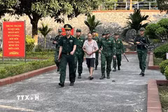 Bộ đội Biên phòng tỉnh Lào Cai áp giải 2 đối tượng trong đường dây xuyên quốc gia đưa người vượt biên trái phép. (Ảnh: TTXVN phát)