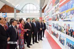 Bí thư Đảng ủy, Tổng Giám đốc TTXVN Vũ Việt Trang giới thiệu với Chủ tịch nước Lương Cường, nguyên Thủ tướng Nguyễn Tấn Dũng và các đại biểu tham quan triển lãm ảnh về Đại hội. (Ảnh: TTXVN)