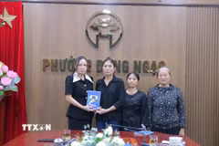 Phó Chủ tịch UBND phường Đông Ngạc Nguyễn Thị Hương trao kinh phí hỗ trợ của phường đến gia đình nạn nhân. (Ảnh TTXVN phát)