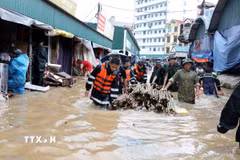 Cán bộ chiến sỹ Bộ Chỉ huy Quân sự tỉnh Lạng Sơn giúp tiểu thương di chuyển tài sản ra khỏi khu vực ngập sâu. (Ảnh: Văn Đạt/TTXVN)