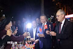 Tổng thống Thụy Sĩ Guy Parmelin bày tỏ sự thích thú với sản phẩm tò he của những nghệ nhân làng Xuân La - nét văn hóa dân gian Việt Nam độc đáo trên phố đi bộ hồ Hoàn Kiếm. (Ảnh: Thống Nhất/TTXVN)