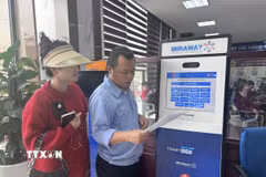 Cán bộ hướng dẫn thủ tục lấy số cho người dân tại Trung tâm Dịch vụ công Thành phố Vinh. (Ảnh: Bích Huệ/TTXVN)