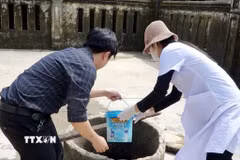 Cán bộ y tế hỗ trợ người dân xử lý nguồn nước sinh hoạt sau lũ. (Ảnh: TTXVN phát)