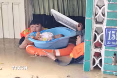 Lực lượng chức năng hỗ trợ đưa trẻ em ra khỏi căn nhà bị ngập sâu ở phường Tây Nha Trang (Khánh Hòa). (Ảnh: Nguyễn Thành/TTXVN)