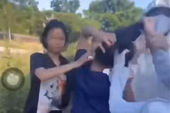 Nữ sinh (áo đen, thứ 2 từ trái sang) bị nhóm bạn túm tóc, liên tục đánh vào phần đầu. (Ảnh cắt từ video)