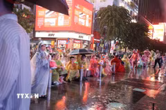Người hâm mộ Thành phố Hồ Chí Minh đội mưa tập trung tại phố đi bộ Nguyễn Huệ trước trận chung kết lượt về. (Ảnh: Hồng Đạt/TTXVN)