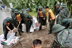 Lực lượng bộ đội hỗ trợ đắp đê bao ngăn nước khu dân cư ven sông Bùi. (Ảnh: Nhật Anh/TTXVN)