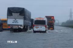 Các phương tiện di chuyển chậm qua một đoạn đường bị ngập nước (Ảnh: Hoàng Hiếu/TTXVN)