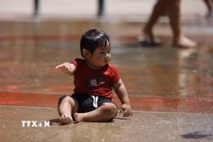 Em nhỏ tránh nóng bên đài phun nước ở Los Angeles, California, Mỹ. (Ảnh: THX/TTXVN phát)