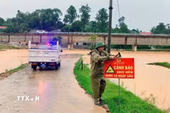 Lực lượng chức năng cắm biển báo ở cung đường ngập lụt. (Ảnh: Công Tường/TTXVN)