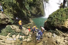 Lực lượng cứu nạn đưa thi thể nạn nhân lên khỏi khu vực chân thác Khâu Làn. (Ảnh: TTXVN phát)