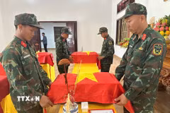 Thành viên Ban Chỉ đạo tìm kiếm, quy tập và xác định danh tính hài cốt liệt sỹ tỉnh Điện Biên thực hiện nghi thức phủ Quốc kỳ lên tiểu sành đựng hài cốt liệt sỹ. (Ảnh: TTXVN phát)