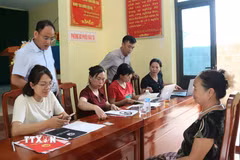 Cán bộ tiếp nhận, kiểm tra hồ sơ, thông tin liên quan đến đất đai của người dân. (Ảnh: Đồng Thúy/TTXVN)