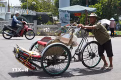 Nhọc nhằn đẩy xe xích lô lên dốc giữa nắng nóng gay gắt ở gần cầu Gia Hội, phường Phú Xuân, thành phố Huế. (Ảnh: Nguyên Lý/TTXVN)