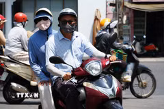 Người dân mặc đồ bảo hộ chống nắng nóng gay gắt khi di chuyển trên đường Trần Hưng Đạo, phường Phú Xuân, Thành phố Huế. (Ảnh: Nguyên Lý/TTXVN)