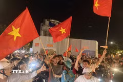 Người dân mang theo cờ Tổ quốc diễu hành trên các tuyến phố Hà Nội để mừng chiến thắng. (Ảnh: An Đăng/TTXVN)