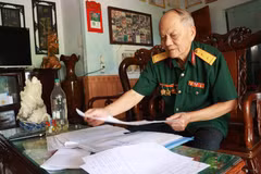 Cựu chiến binh Nguyễn Thanh Bình cẩn thận ghi chép, lưu giữ thông tin tên, ngày hy sinh, đơn vị chiến đấu, quê quán, thân nhân các liệt sỹ. (Ảnh: Tường Vi/TTXVN)