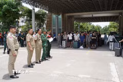 Lực lượng chức năng Việt Nam và Campuchia làm thủ tục bàn giao, tiếp nhận công dân được trao trả. (Ảnh: TTXVN phát)