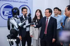 Phó Thủ tướng Hồ Quốc Dũng và các đại biểu tham quan robot tại Trung tâm thực hành tập trung của Trường Đại học Công nghệ. (Ảnh: Hoàng Hiếu/TTXVN)